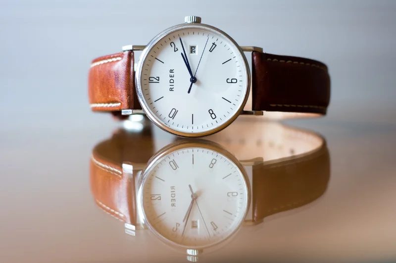 Photograph of a men's wristwatch sitting on a mirrored surface