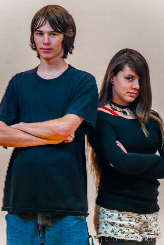 Portrait of a teenaged boy and girl standing back-to-back with arms crossed