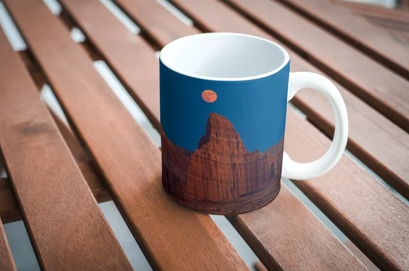 Mockup of a Cramer Imaging landscape photo on a mug sitting on a wooden slat table