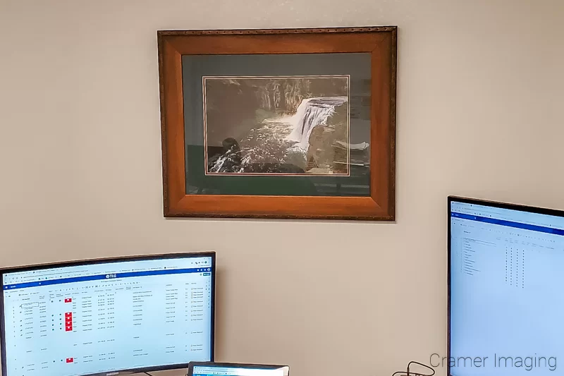 Photograph of Audrey Cramer Photography's fine art photograph 'Upper Mesa Falls' on the wall of a room with a desk and computer