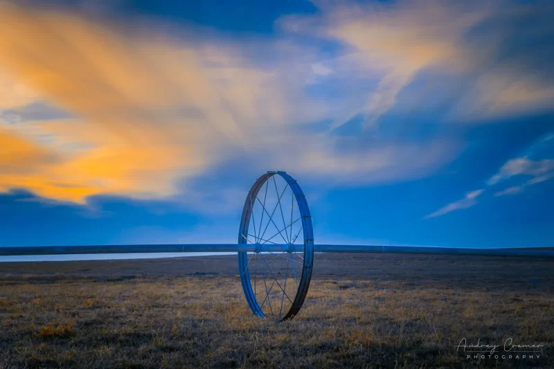 Audrey Cramer Photography's fine art landscape photograph of wheel line irrigation equipment against a dramatic sunset sky in wintertime in Idaho