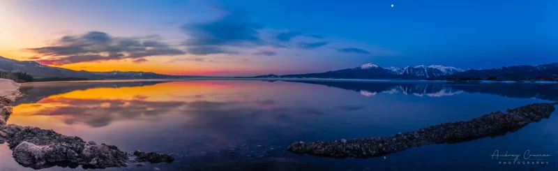 Cramer Imaging's professional quality landscape panorama photograph of the sky and moon reflecting in Henry's Lake at dawn with blue and golden hours