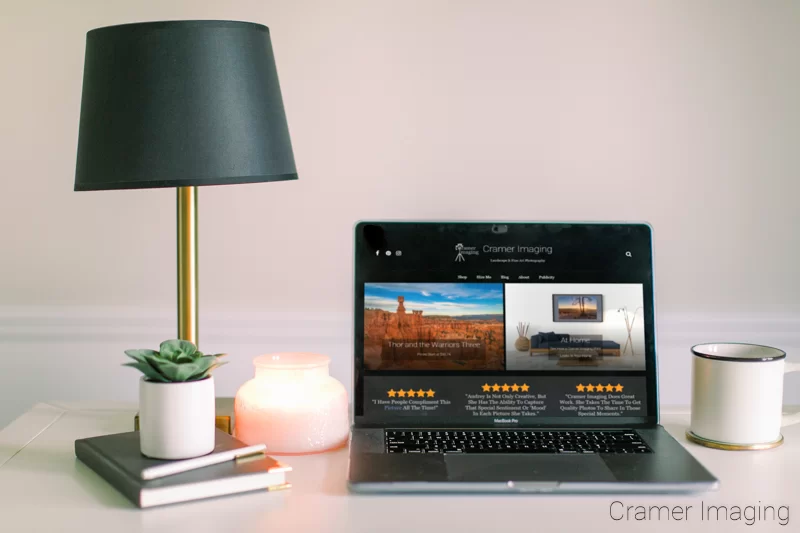 Photograph of a desk surface with the Cramer Imaging website up on a laptop screen