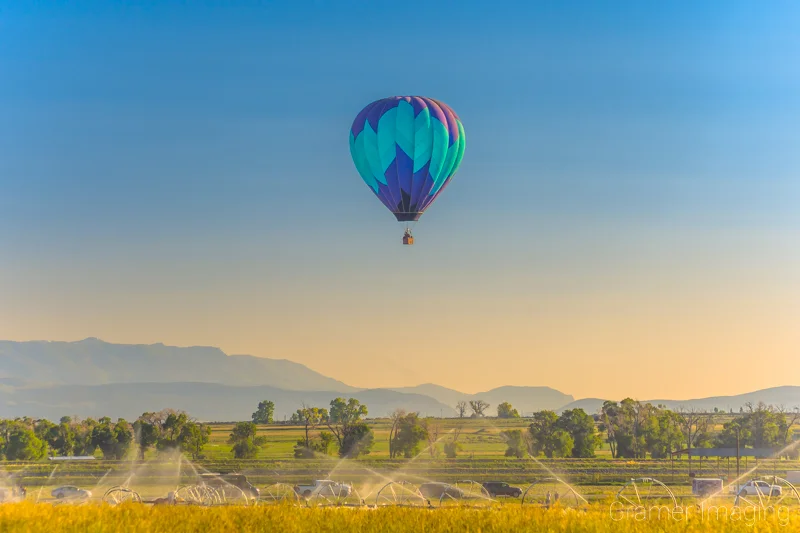 Fine art photograph of a single hot air balloon flying over a farm field in Panguitch, Utah by Audrey Cramer Photography