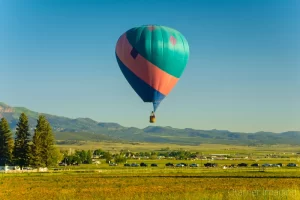 Fine art photograph of a tri-colored hot air balloon soaring over a farm field in Panguitch, Utah by Cramer Imaging