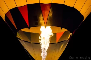 Fine art photograph of a jet of flame shooting up into a hot air balloon at night by Cramer Imaging