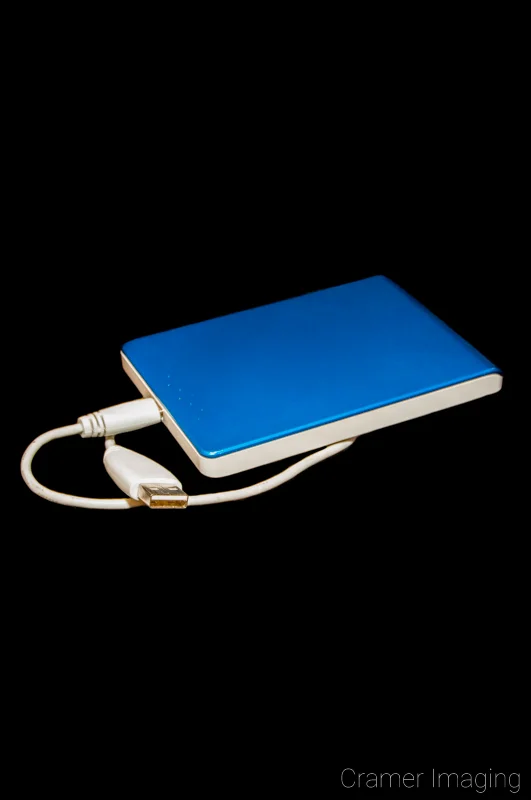 Stock photograph of a blue and white USB external hard drive disk on a black background