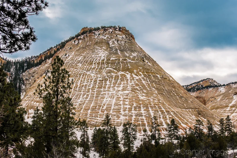 Audrey Cramer Photography's fine art landscape photograph of a snow-covered Checkerboard Mesa with cloudy skies at Zion National Park Utah