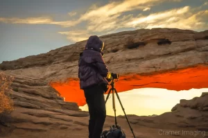 Landscape photographer Audrey Cramer doing an early morning shoot at Mesa Arch, Canyonlands National Park, Utah