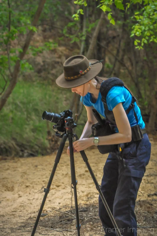 Landscape photographer Audrey Cramer adjusting her tripod for a shot in a forest