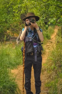 Landscape photographer Audrey Cramer stopping to handhold taking a photo on a forest trail