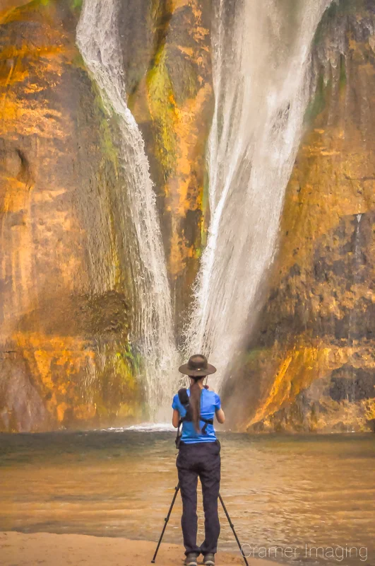 Landscape photographer Audrey Cramer standing in front of and photographing Lower Calf Creek Falls in Escalante National Monument, Utah