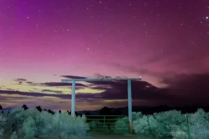 Cramer Imaging's fine art astrophotography photograph of an aurora borealis appearing in the night sky over a light painted cattle gate