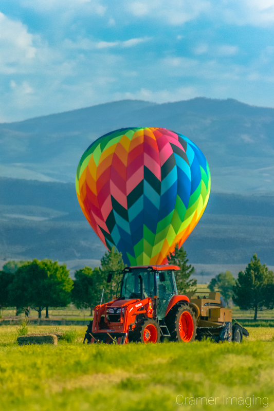 Cramer Imaging's fine art photograph of a hot air balloon landed behind a tractor in a farm field