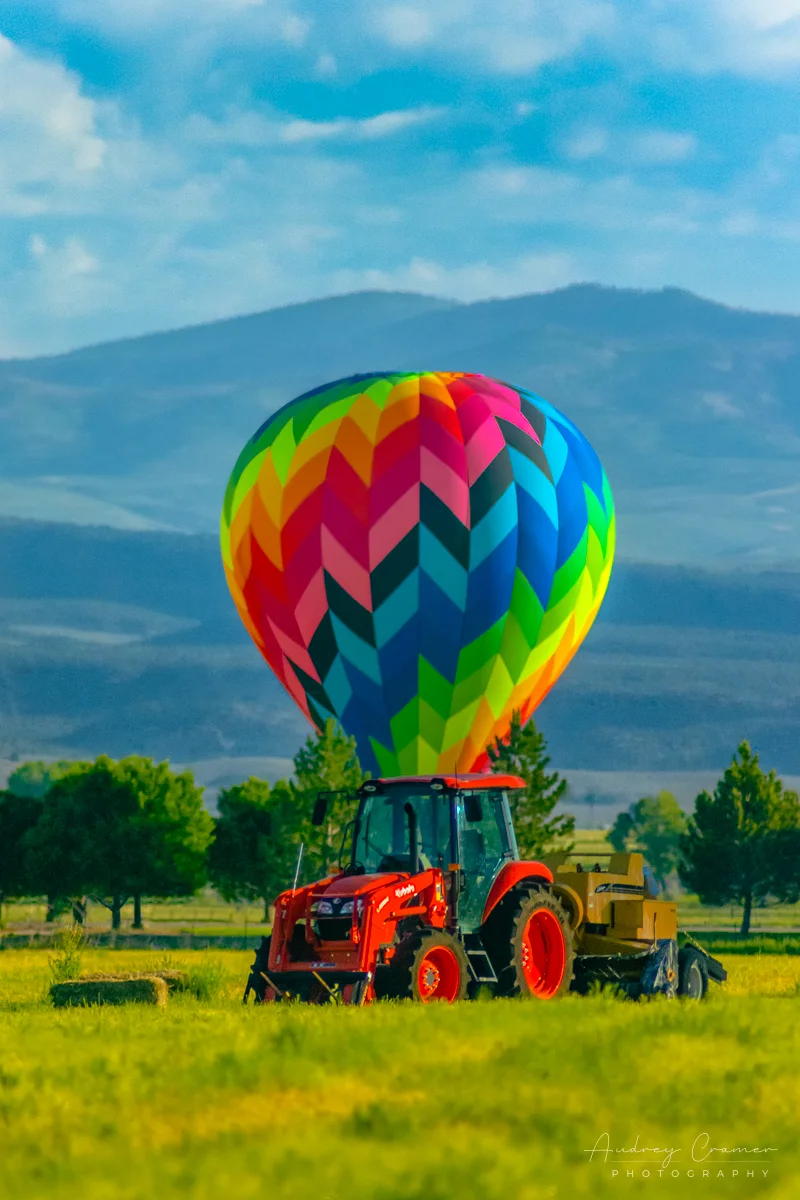 Cramer Imaging's fine art photograph of a hot air balloon landed behind a tractor in a farm field