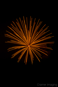 Cramer Imaging's fine art photograph of a yellow-orange firework in the night sky