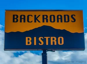 Photo of the Backroads Bistro restaurant sign in Panguitch, Utah against a blue sky with clouds