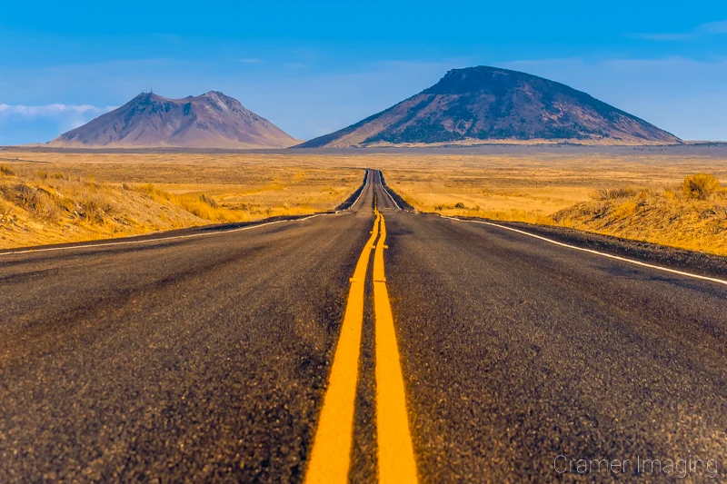 Audrey Cramer Photography's fine art landscape photograph of a road leading out to two buttes in the desert near Arco, Idaho