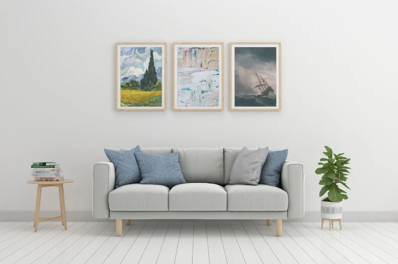 Photo of three dusty old paintings on the wall of a cool-tone living room