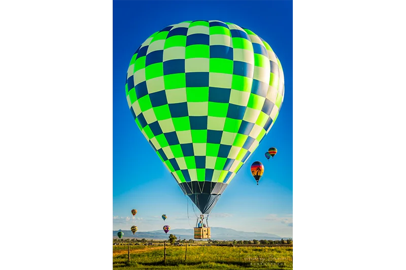 Fine art landscape photograph of a bright hot air balloon flying over a fence in Panguitch, Utah, by Audrey Cramer Photography