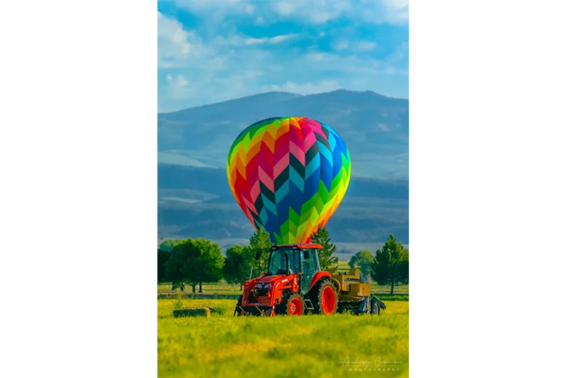 Audrey Cramer Photography's fine art photograph of a hot air balloon landed behind a tractor in a farm field