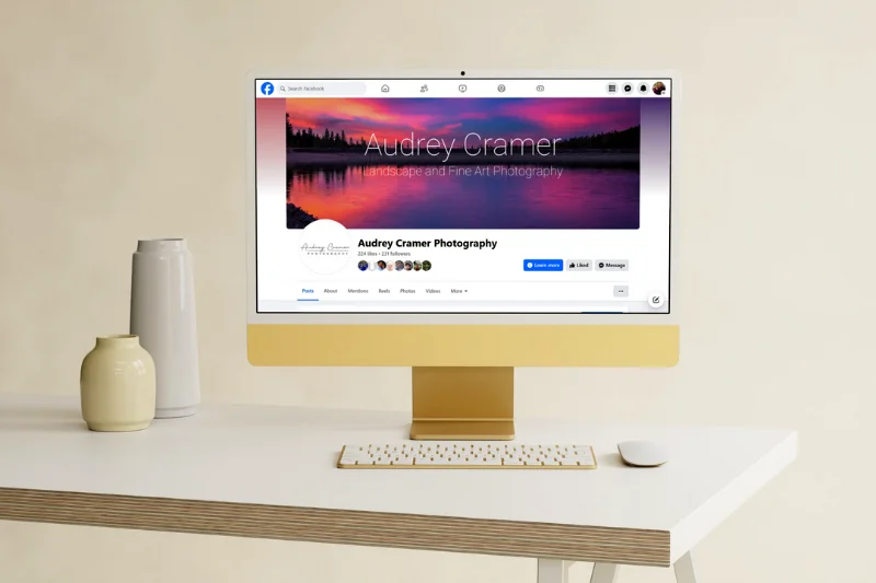 Mockup of a computer desk with the Audrey Cramer Photography Facebook page on screen