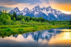 Audrey Cramer Photography's fine art landscape photograph of light from the setting sun beaming out from behind the Teton mountains with ducks swimming in the river in Grand Teton National Park, Wyoming